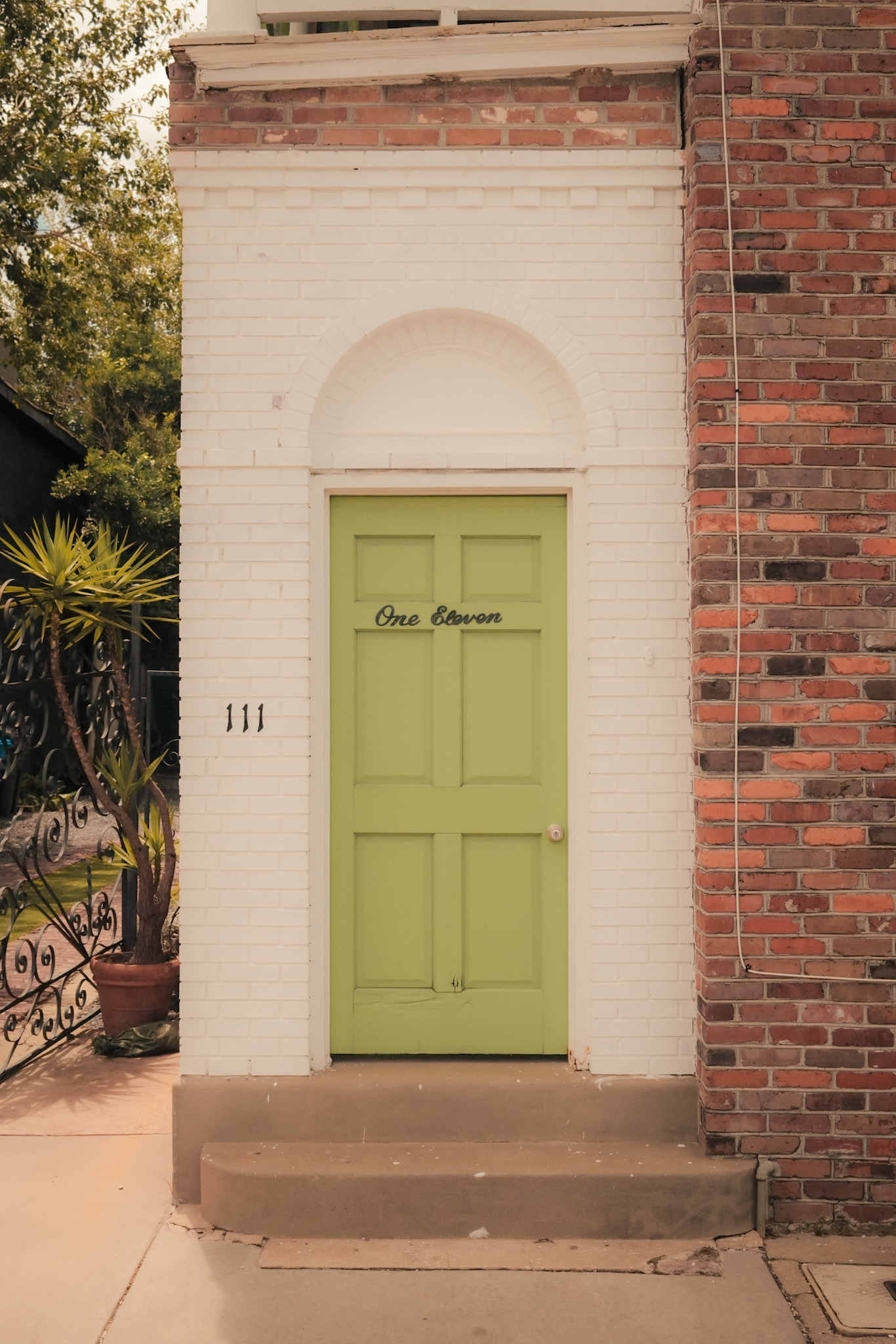 The green front door of the One Eleven Group studio in Raleigh, NC — with the numeral 111 on the wall and 'One Eleven' hand-lettered on the door